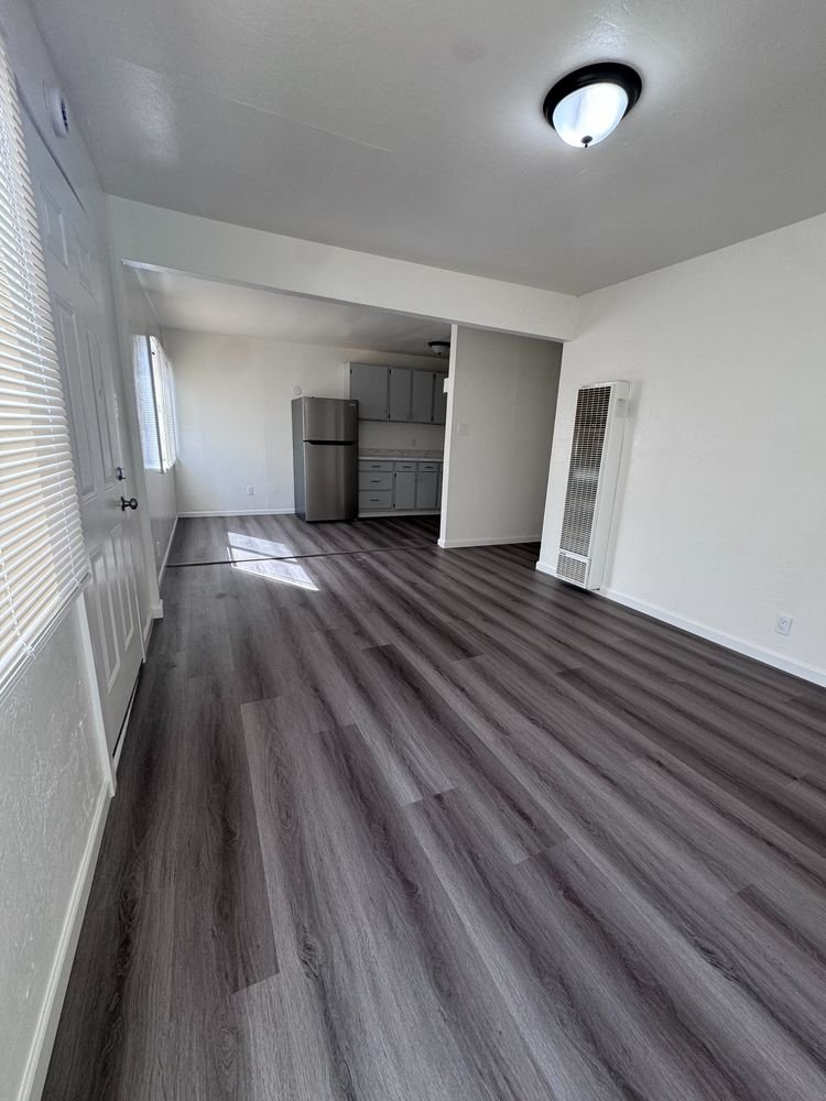 Bright living area with new plank flooring looking toward the kitchen