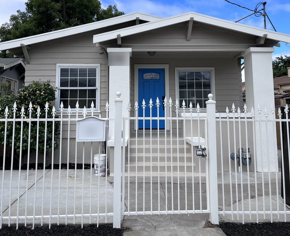 One of our flips: a renovated single-family house with a blue front door and white fence